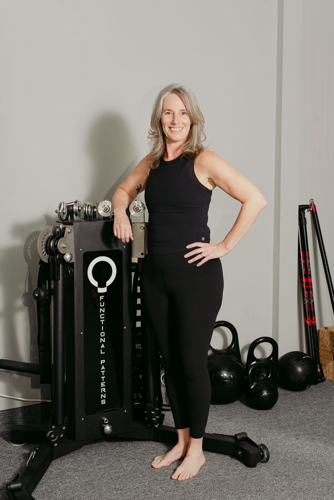 Dr. Kimberly Berkus standing beside a Functional Patterns training machine in her studio.